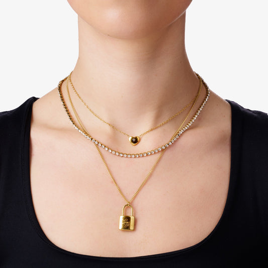 Close-up of a woman wearing a triple-layer 18K gold-plated necklace, featuring a zircon-studded middle layer and a lock-shaped locket on the final layer, showcasing hypoallergenic jewelry perfect for sensitive skin.