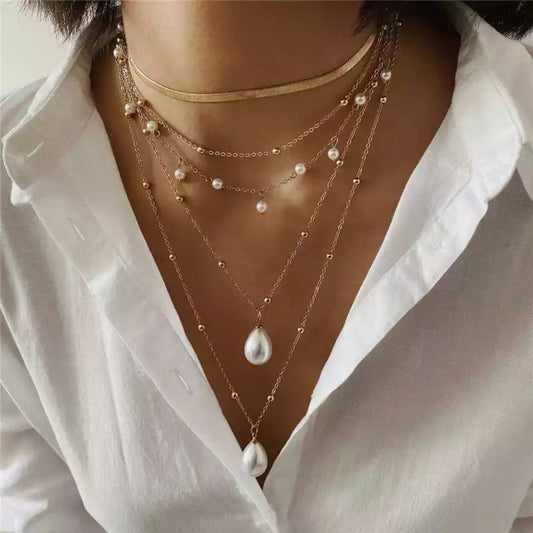 Close-up of multiple pearl necklaces with 18K gold-plated chains around woman’s neck