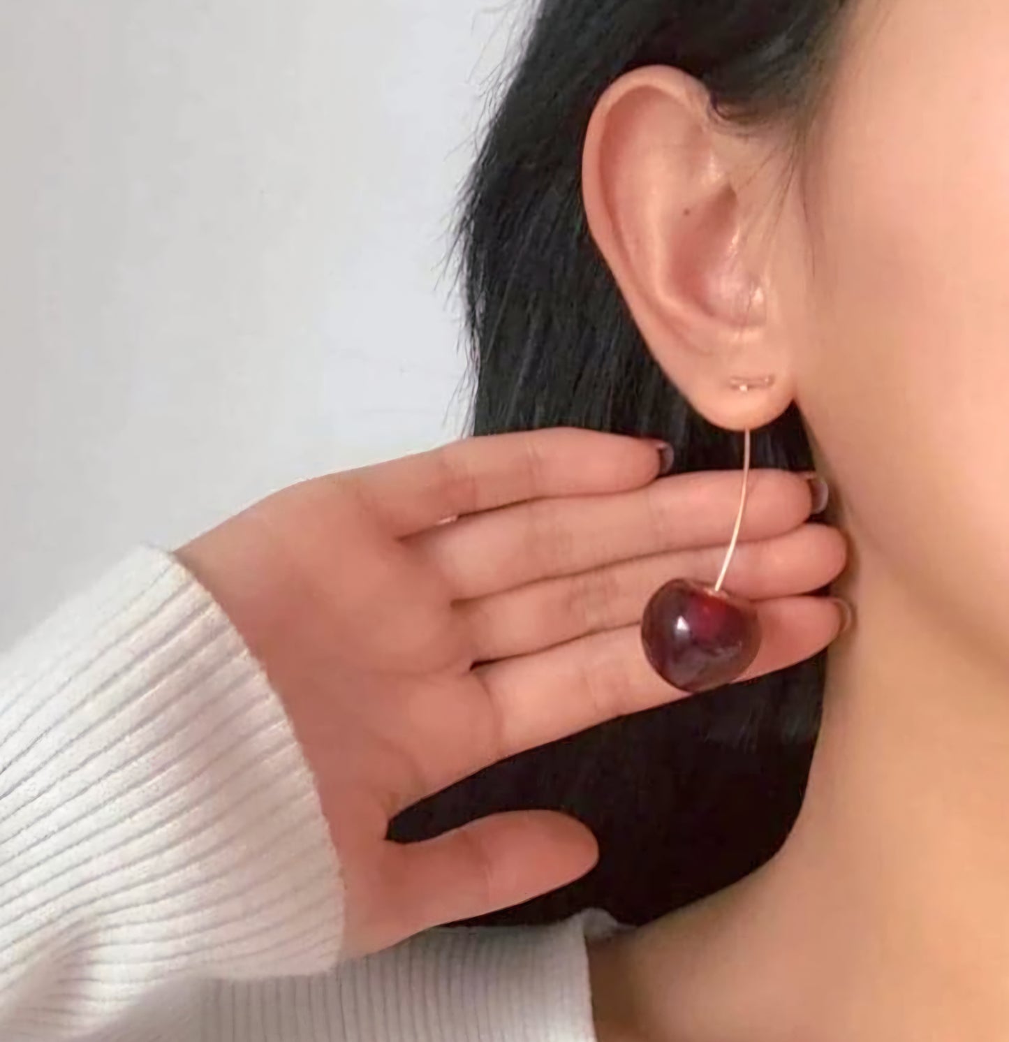 Model wearing TISA gold cherry drop earrings – playful red enamel design, waterproof and safe for sensitive ears