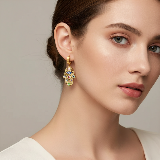 Close-up of a woman wearing a hamsa hand 18k gold plated earring on a neutral background