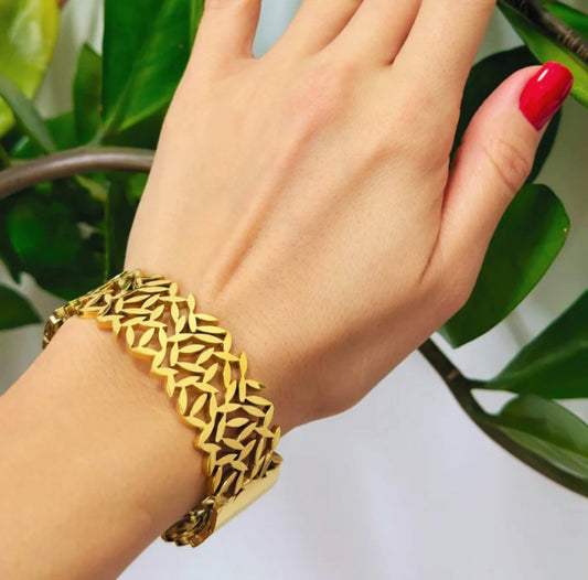 Model wearing 18k gold plated bangle with a plant in the background.
