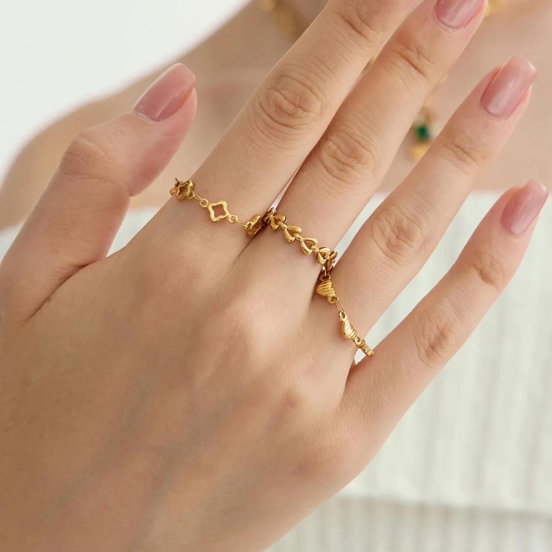 3 gold adjustable chain rings with intricate design on a hand against a neutral background