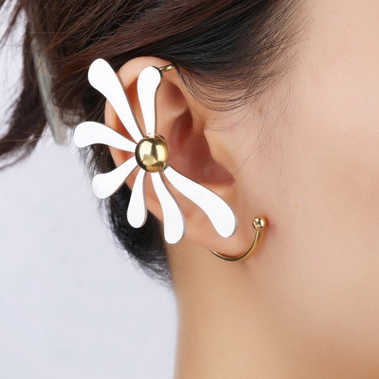 Close-up of a white flower-shaped dual tone ear cuff with gold accents on an ear against a neutral background