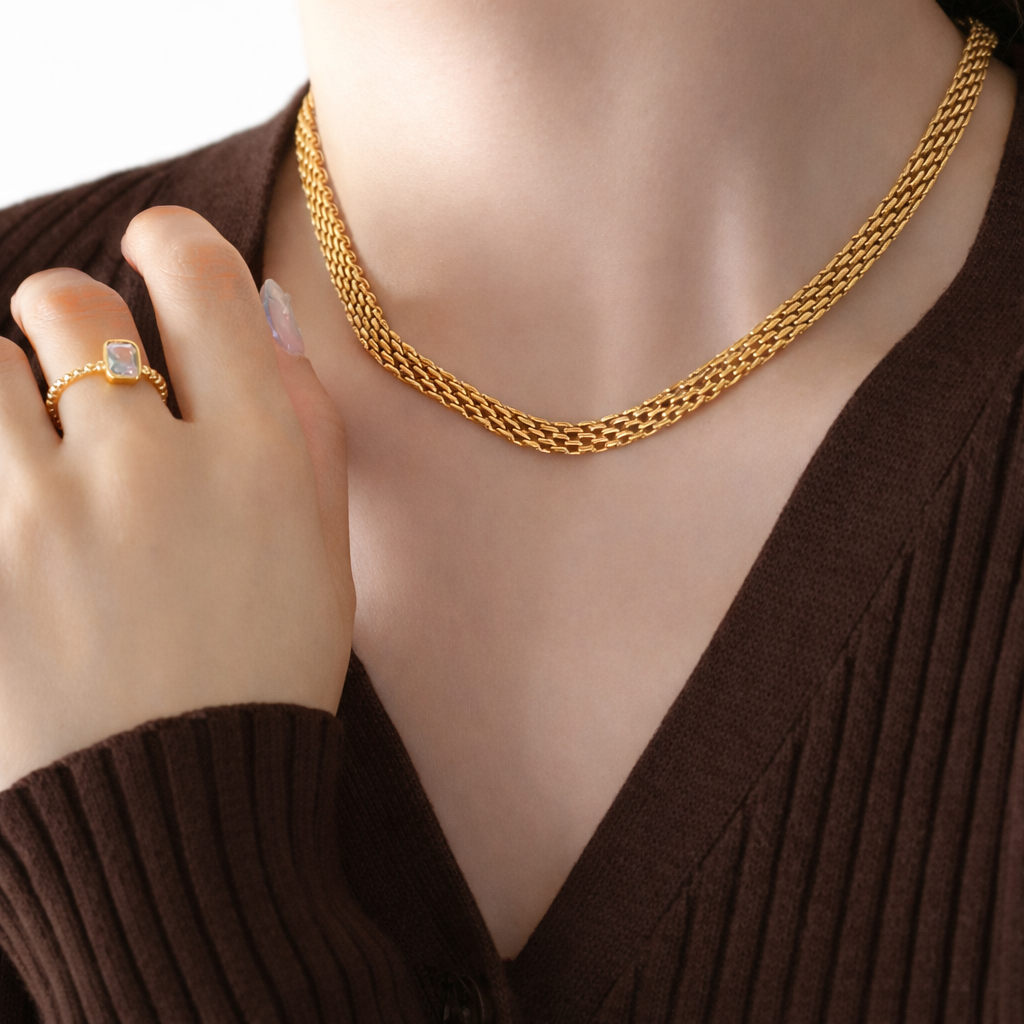18k gold plated double curb chain necklace on a model with a hand wearing a ring, against a neutral background