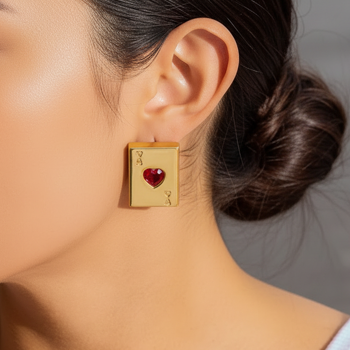 Close-up of a person wearing a poker  18k gold plated stainless steel earring with a red heart design