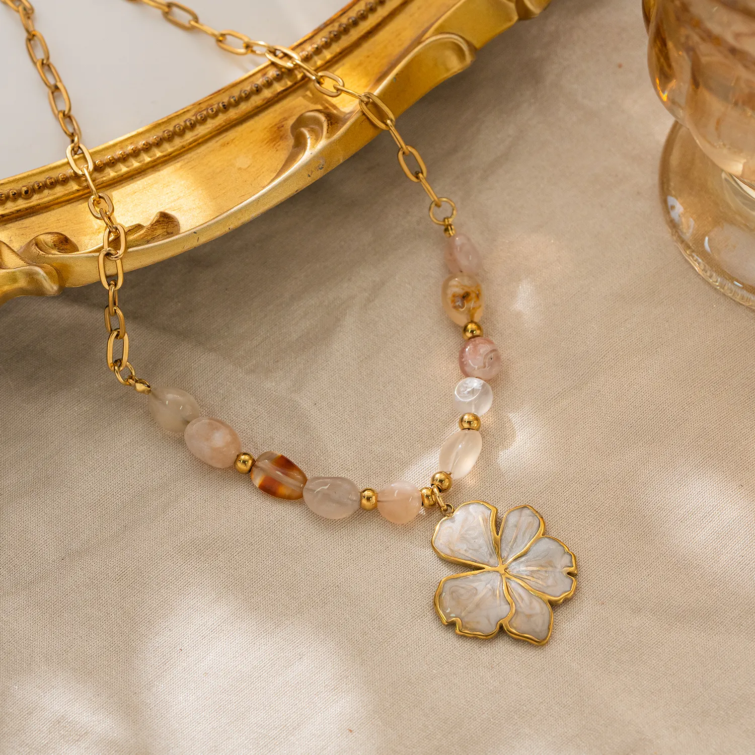 Necklace with a floral pendant and beaded chain on a beige fabric background