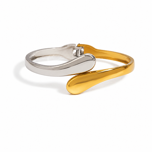 A two-tone metal cuff bracelet featuring a polished silver-toned band and a curved gold-toned accent, displayed on a clean white background.