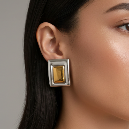 Close-up of a woman wearing a dual-tone 18k stainless steel earring on a neutral background