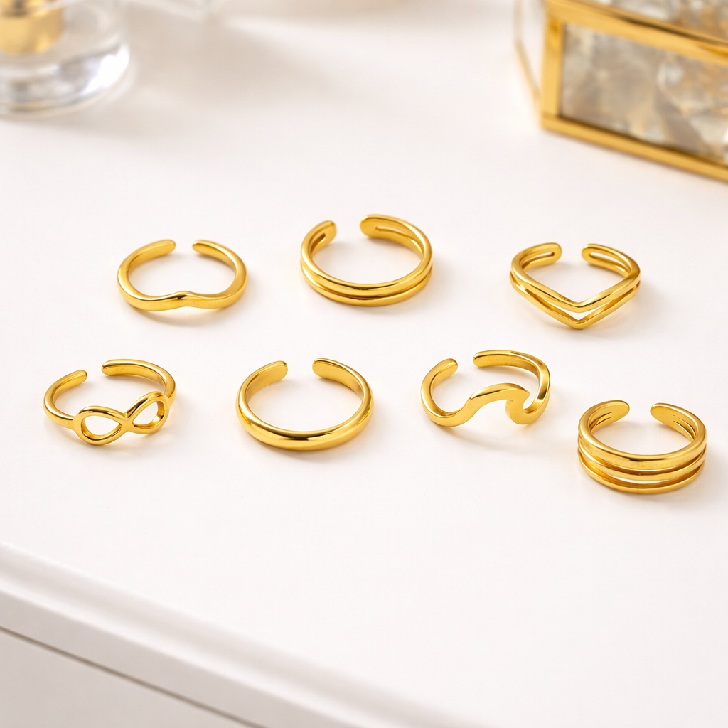 Set of Tisa 18k gold plated pinky rings on a white surface with a decorative box in the background.
