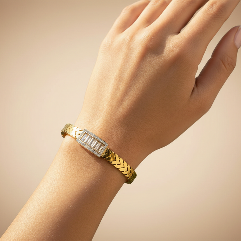 Tisa 18k gold plated bracelet with diamond accents on a wrist against a beige background.