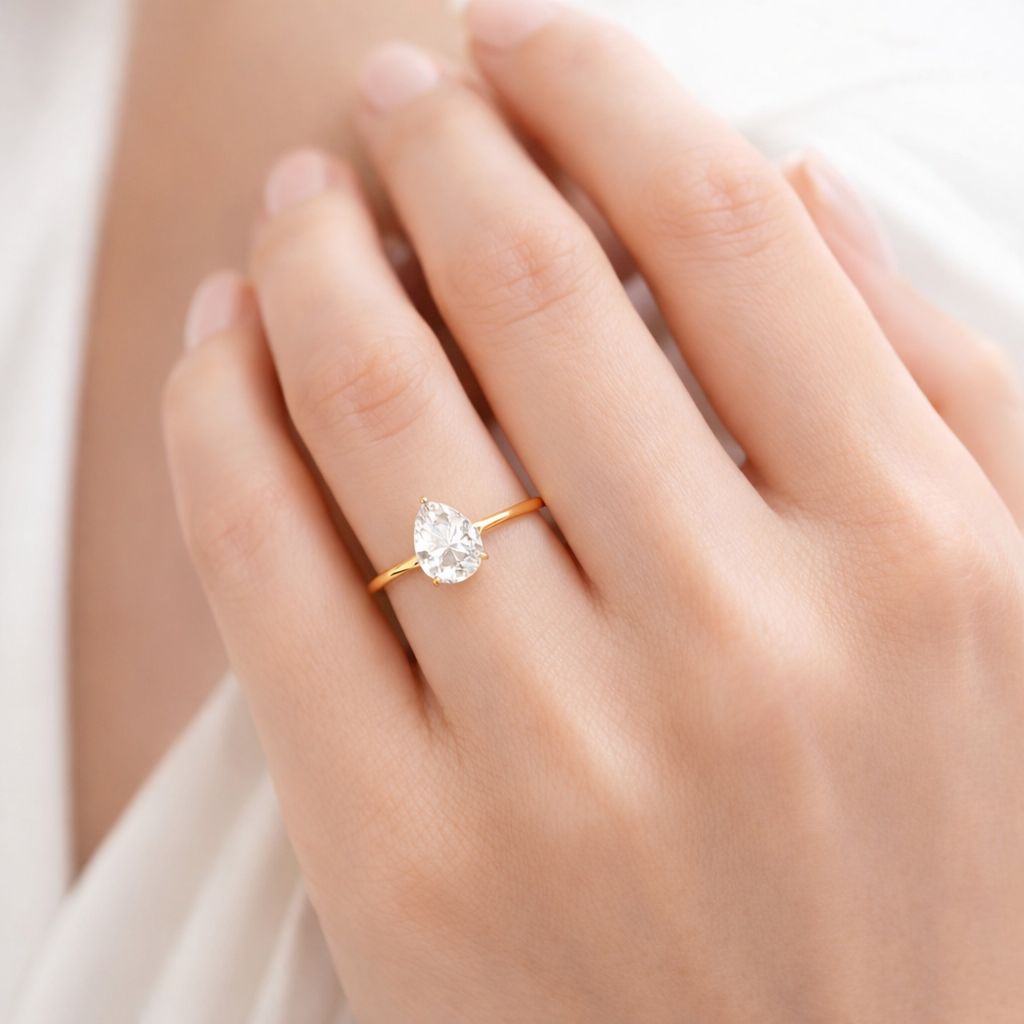 Dainty 18k gold plated ring with a pear-shaped zircon on hand of a model