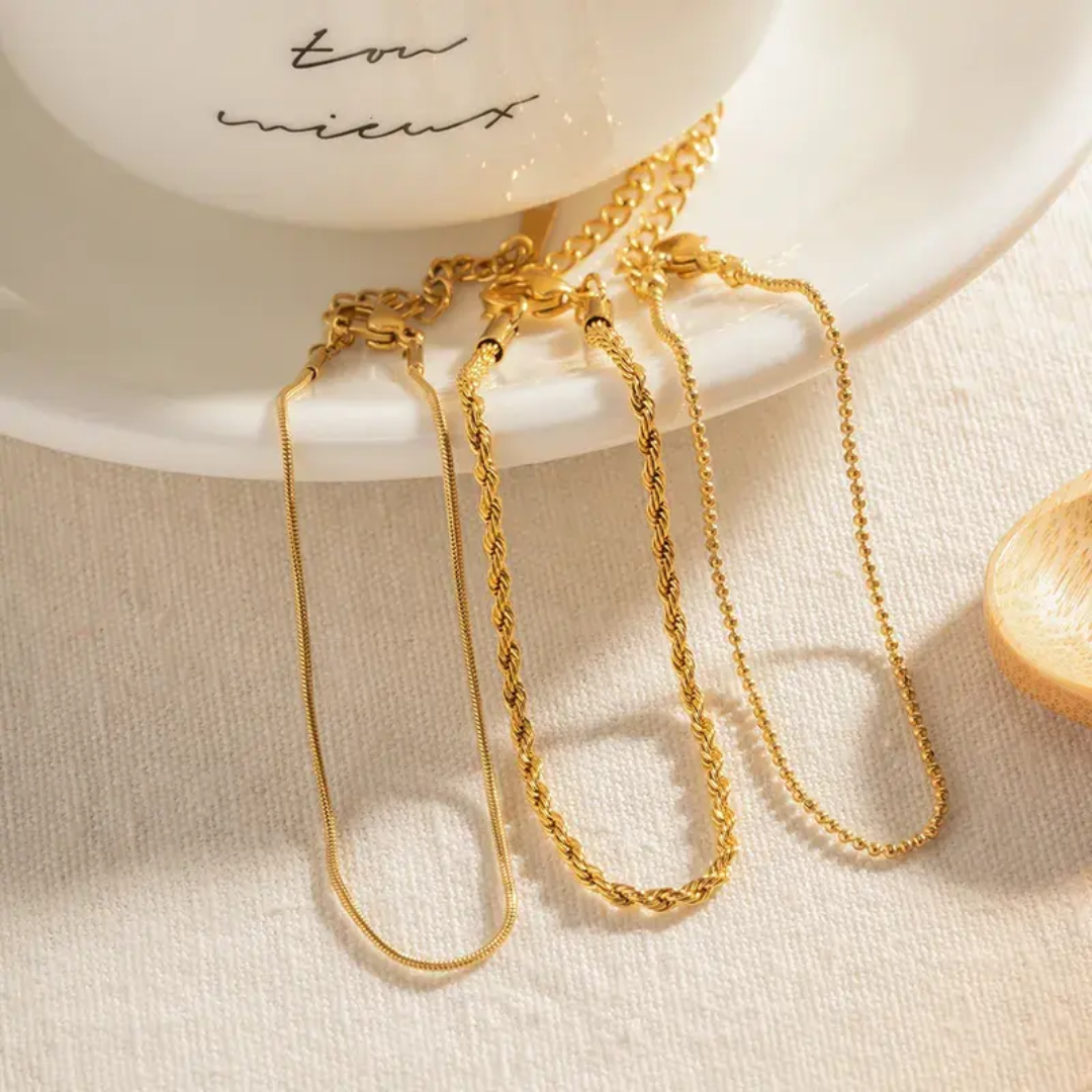 Three 18k gold-plated bracelets kept on a white dish with 'love' and 'united' text.