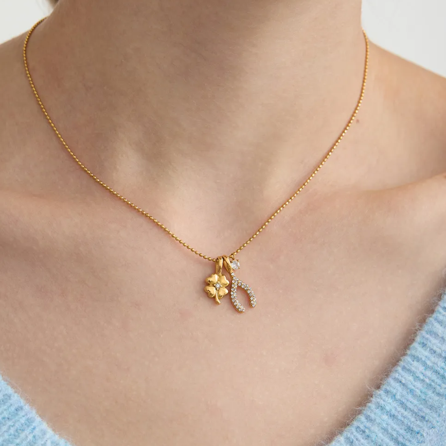 Tisa 18k Gold-plated  necklace with charms on a person wearing a light blue sweater.