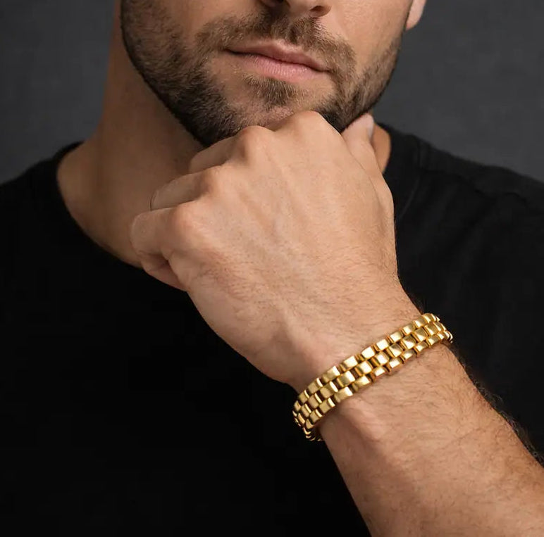 Male model wearing Tisa 18k gold-plated stainless steel bracelet on a dark background.
